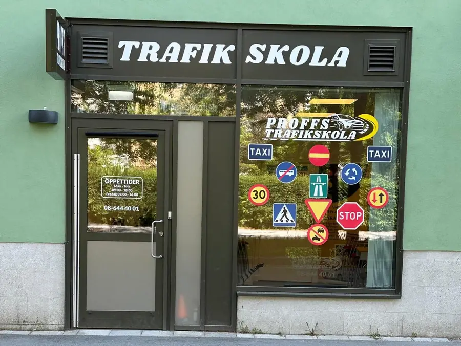 Entrén till Proffs Trafikskola med skolans skylt och trafikmärken i fönstret